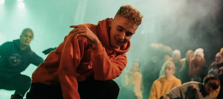 En ung mann breakdancer på mørk scene foran publikum