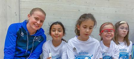 En innebandytrener og fire spillere smiler